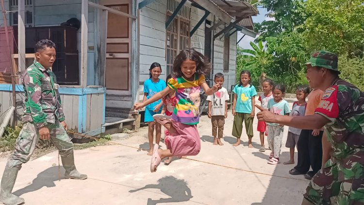 Personil Satgas Memanfaatkan Waktu Istirahat Bermain dengan Anak - anak di Lokasi TMMD